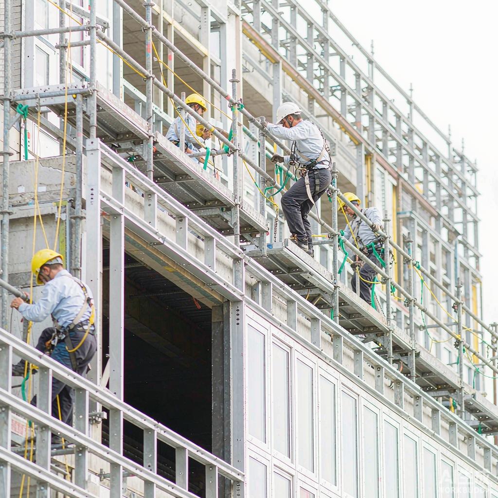 Construction workers installing stick-built aluminium curtain wall on site