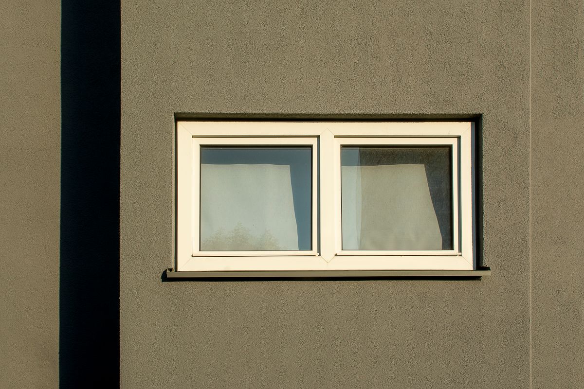 Minimalist aluminium tilt and turn window set in a rendered wall