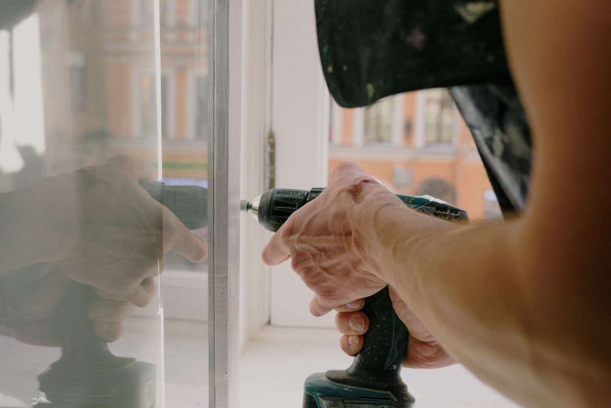 Technician fastening multi-point locking hardware on an aluminium window sash