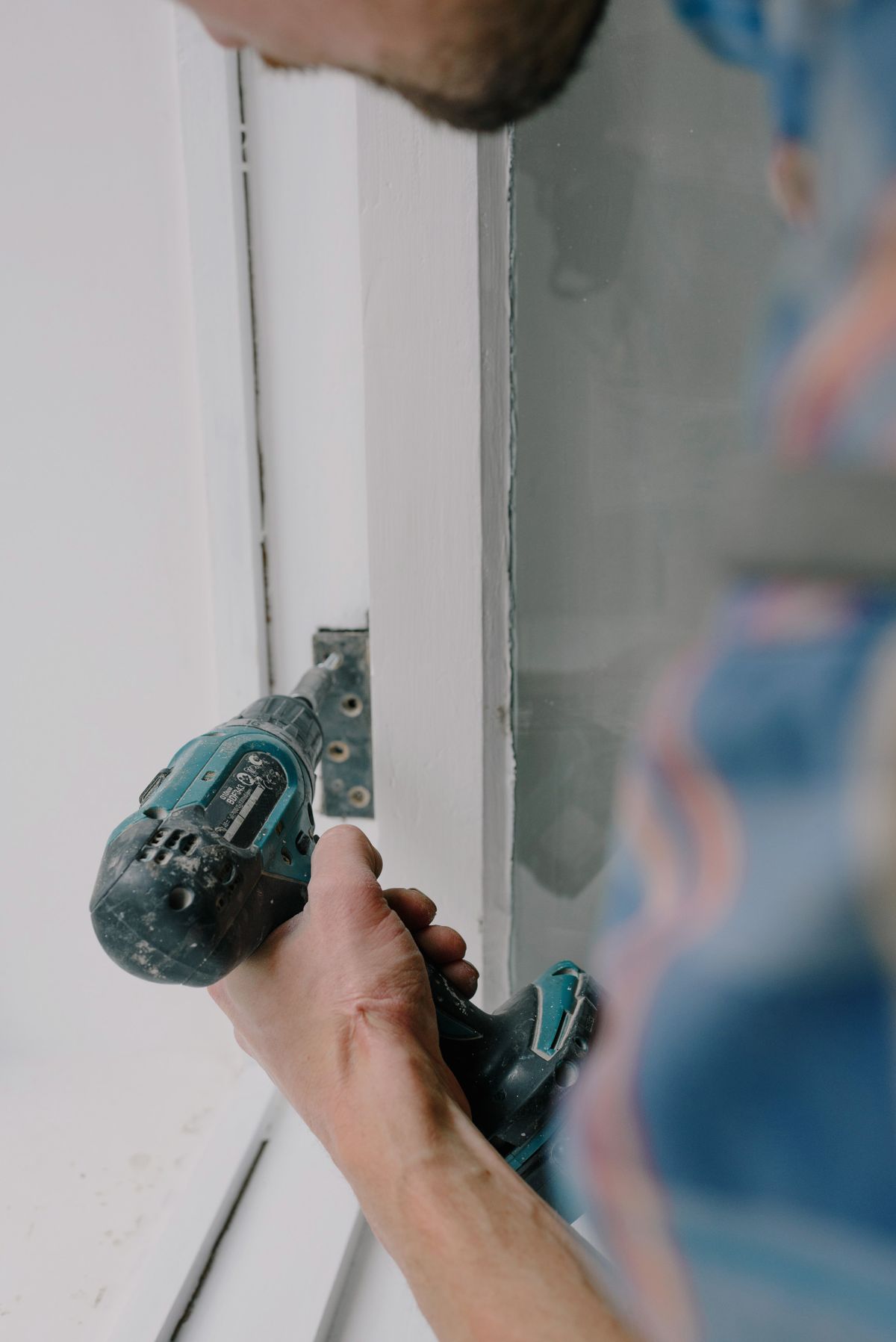 Technician fixing a window frame with a screwdriver during installation